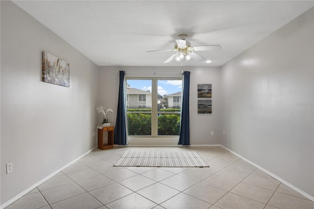 spare room featuring ceiling fan, light tile patterned flooring, and a textured ceiling