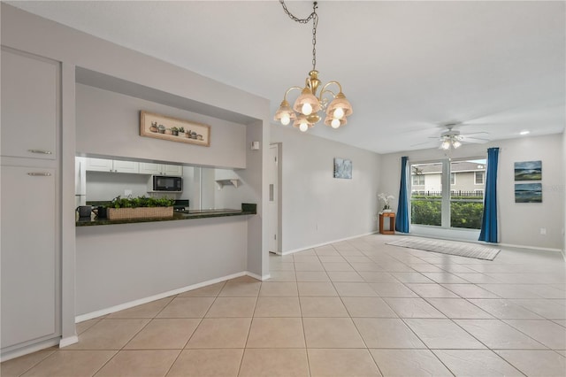 tiled spare room with ceiling fan with notable chandelier