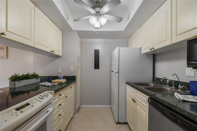 kitchen featuring ceiling fan, a raised ceiling, light tile patterned floors, sink, and white appliances