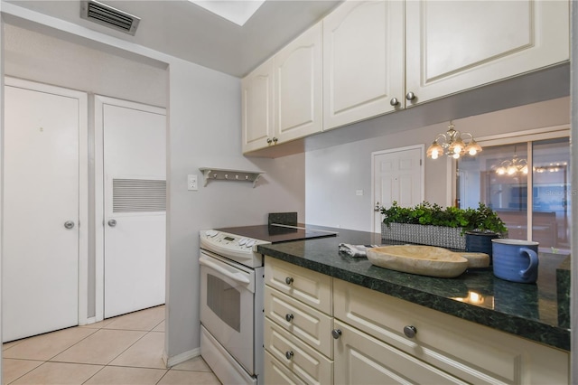 kitchen with electric stove, an inviting chandelier, dark stone counters, and light tile patterned floors