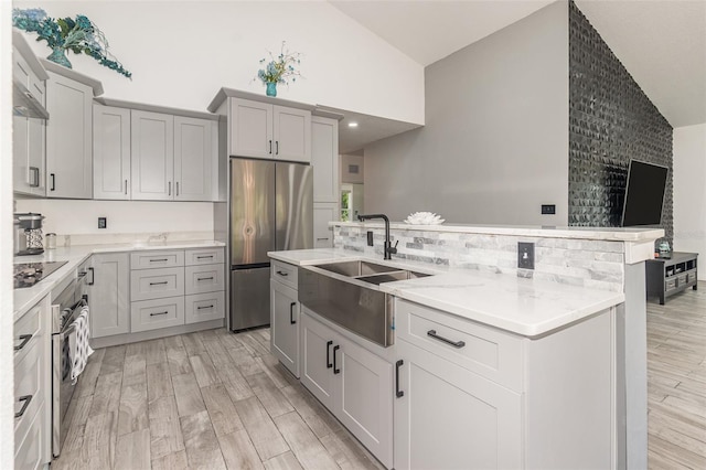 kitchen with sink, gray cabinetry, a center island with sink, light hardwood / wood-style flooring, and appliances with stainless steel finishes