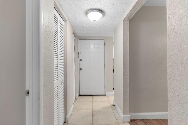 hall with a textured ceiling and light tile patterned floors