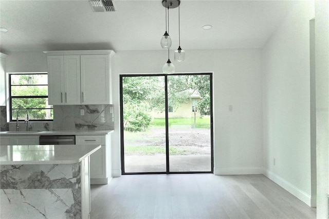 kitchen with light wood-type flooring, hanging light fixtures, sink, and white cabinetry