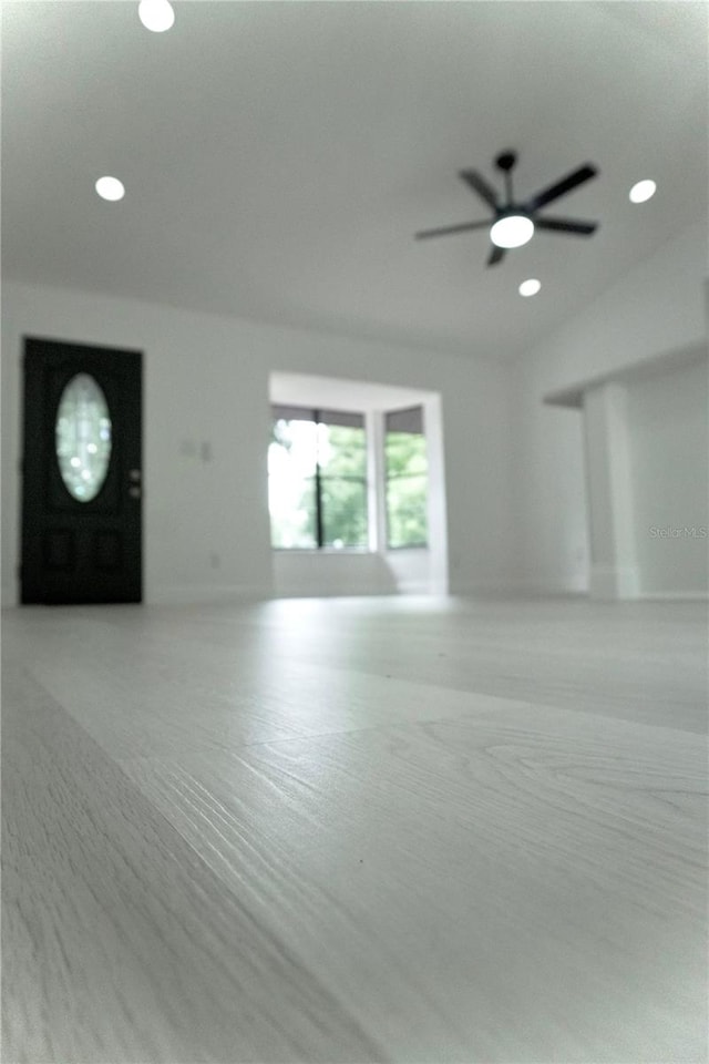 unfurnished living room with lofted ceiling, ceiling fan, and light colored carpet