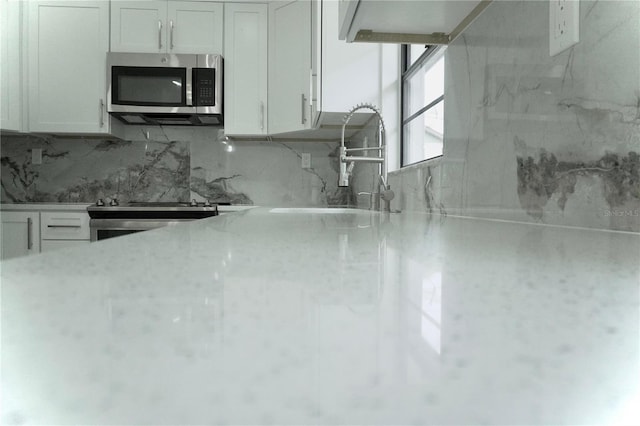 kitchen featuring decorative backsplash, white cabinetry, sink, and stainless steel appliances