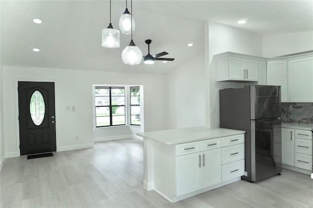 kitchen with light hardwood / wood-style floors, white cabinetry, kitchen peninsula, ceiling fan, and stainless steel fridge