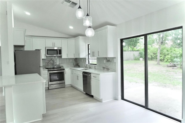 kitchen featuring appliances with stainless steel finishes, lofted ceiling, decorative light fixtures, and white cabinets