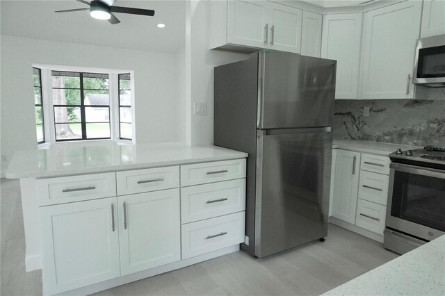 kitchen featuring ceiling fan, stainless steel appliances, and white cabinetry