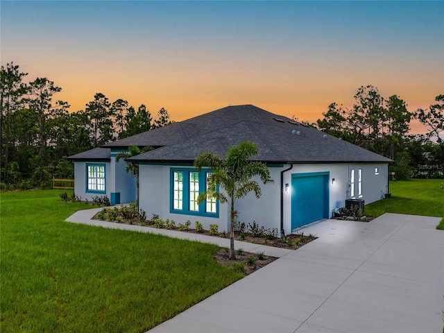 view of front of home featuring a lawn, cooling unit, and a garage