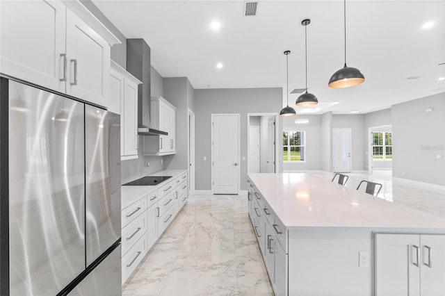 kitchen featuring a large island, pendant lighting, white cabinets, wall chimney exhaust hood, and stainless steel fridge