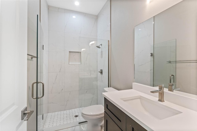 bathroom featuring vanity, toilet, and a shower with door