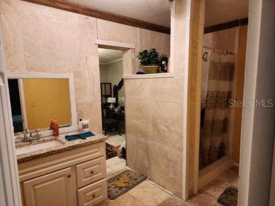 bathroom with ornamental molding, curtained shower, and vanity