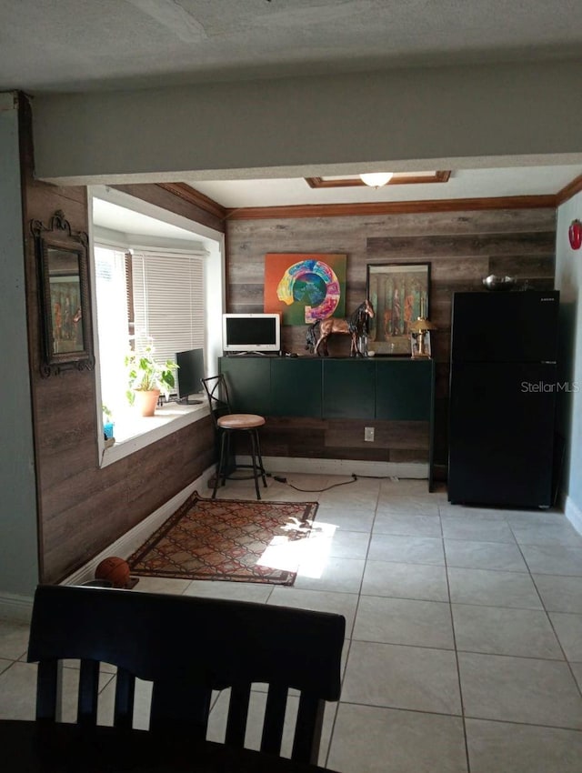 interior space with black refrigerator, beam ceiling, light tile patterned floors, and wood walls