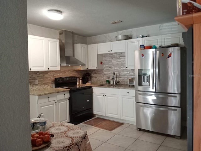 kitchen featuring white cabinetry, wall chimney exhaust hood, stainless steel fridge, and black electric range