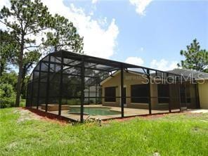 rear view of house with a patio area, a lanai, and a lawn