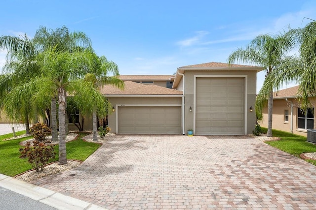 view of front of property featuring stucco siding, driveway, an attached garage, and roof with shingles