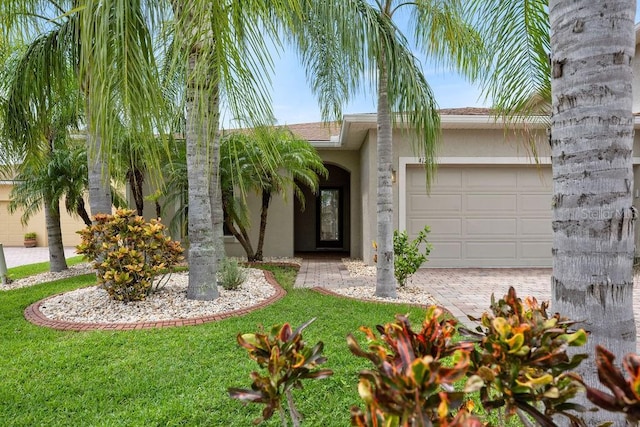 view of front of house featuring decorative driveway, stucco siding, an attached garage, and a front lawn