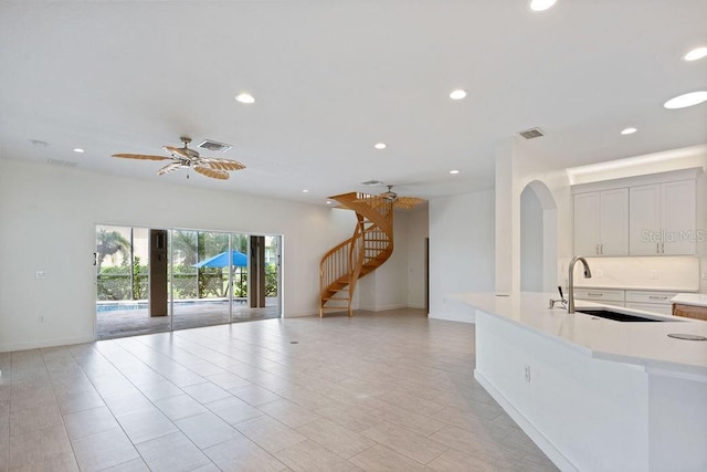 unfurnished living room featuring stairs, visible vents, recessed lighting, and a sink