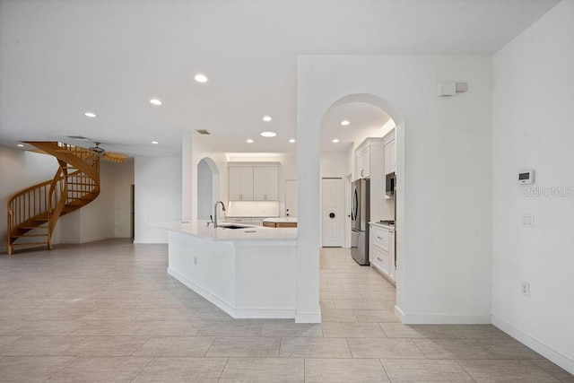 kitchen featuring light countertops, a sink, stainless steel appliances, arched walkways, and recessed lighting