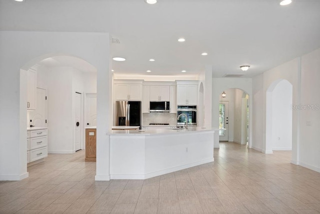 kitchen featuring sink, an island with sink, white cabinets, decorative backsplash, and stainless steel appliances