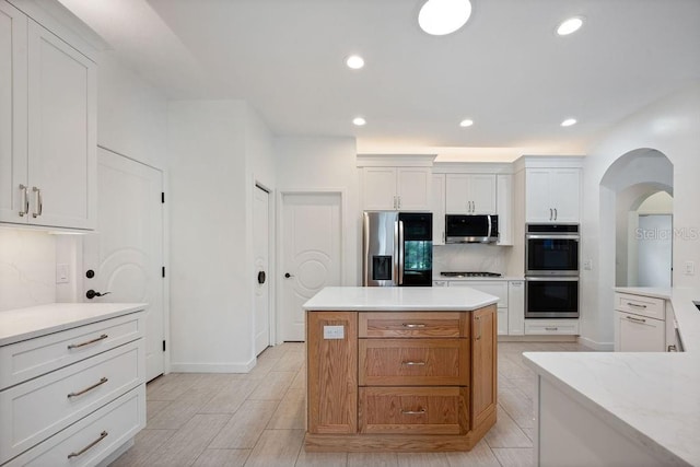 kitchen with light stone counters, white cabinets, appliances with stainless steel finishes, and a center island