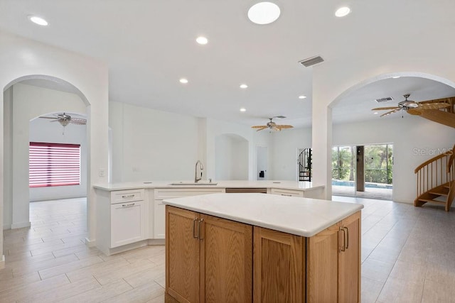 kitchen featuring kitchen peninsula, sink, ceiling fan, and white cabinets