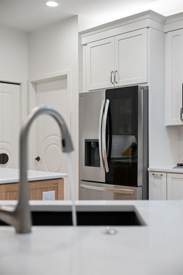 kitchen with stainless steel refrigerator with ice dispenser and white cabinetry