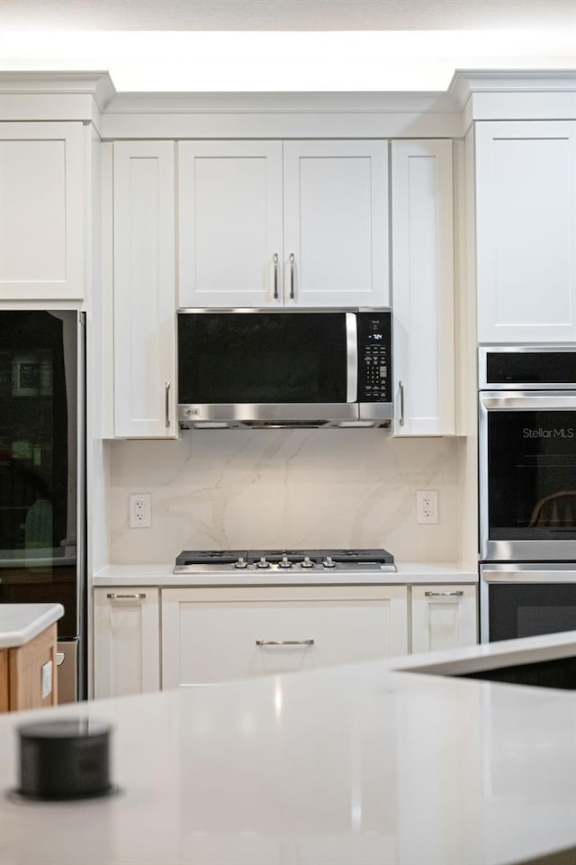 kitchen featuring white cabinetry, light countertops, appliances with stainless steel finishes, and decorative backsplash