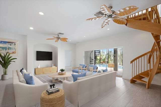 living room with ceiling fan, visible vents, and stairway