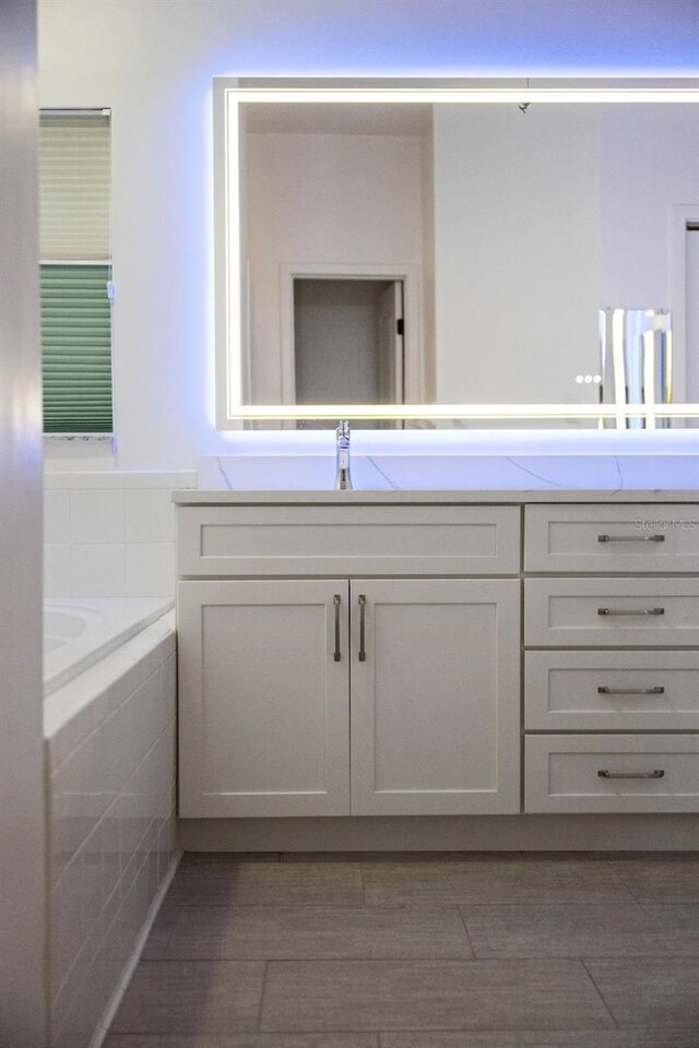 bathroom featuring a relaxing tiled tub and vanity