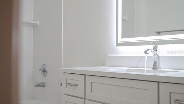 bathroom with a tile shower and vanity