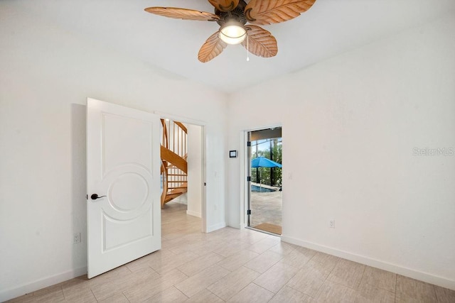 empty room featuring light wood finished floors, baseboards, stairs, and ceiling fan