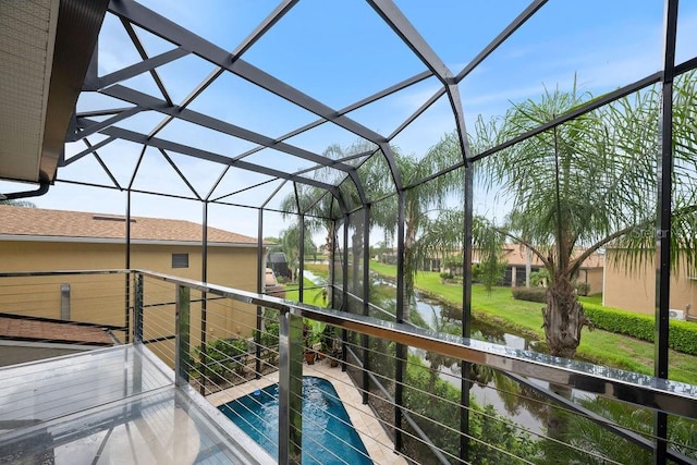 view of swimming pool featuring glass enclosure and a water view