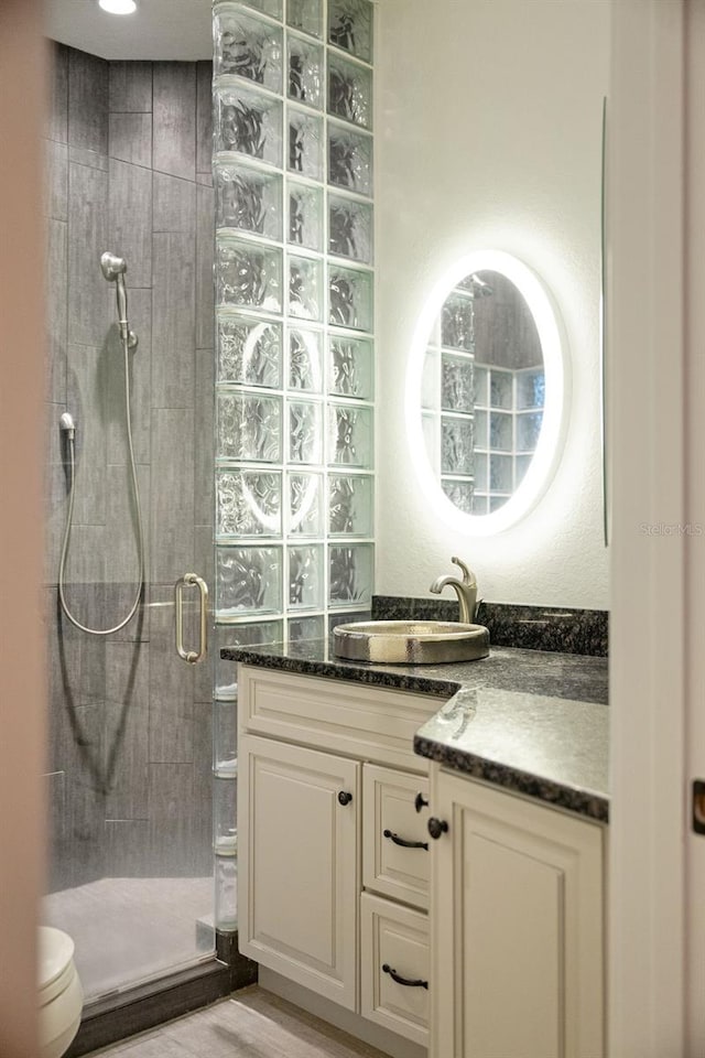 bathroom with toilet, vanity, a stall shower, and wood finished floors
