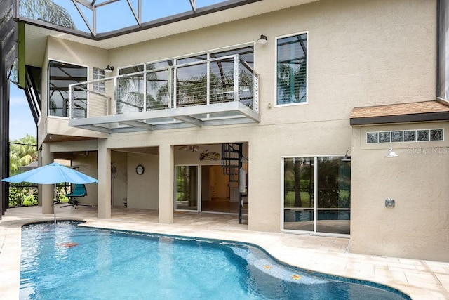 rear view of house featuring a balcony, stucco siding, and a patio