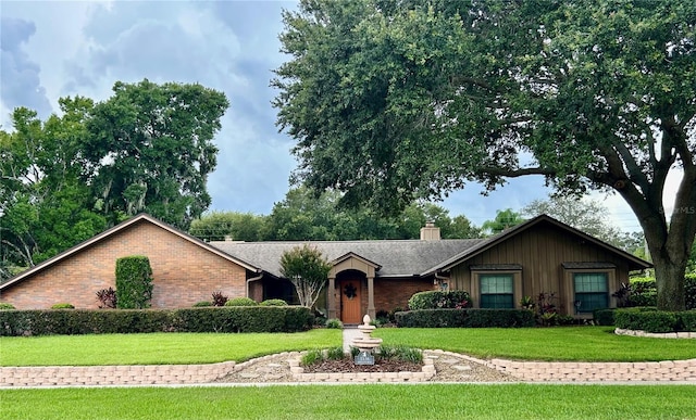 ranch-style house with a chimney, a front lawn, and brick siding