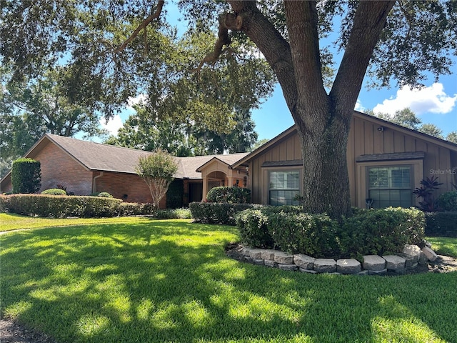 view of front of house featuring brick siding, board and batten siding, and a front yard