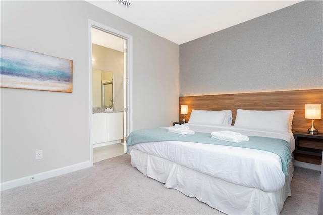 bedroom with connected bathroom and light colored carpet