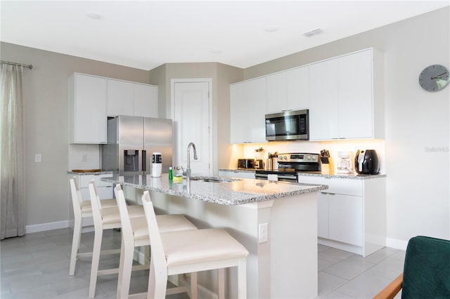 kitchen featuring white cabinets, an island with sink, appliances with stainless steel finishes, and sink