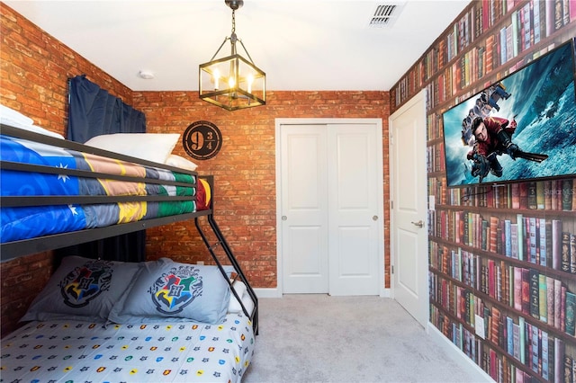 carpeted bedroom with a chandelier and brick wall