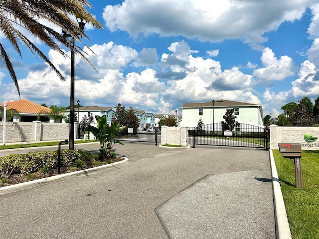 view of street with a gate, a residential view, a gated entry, and curbs