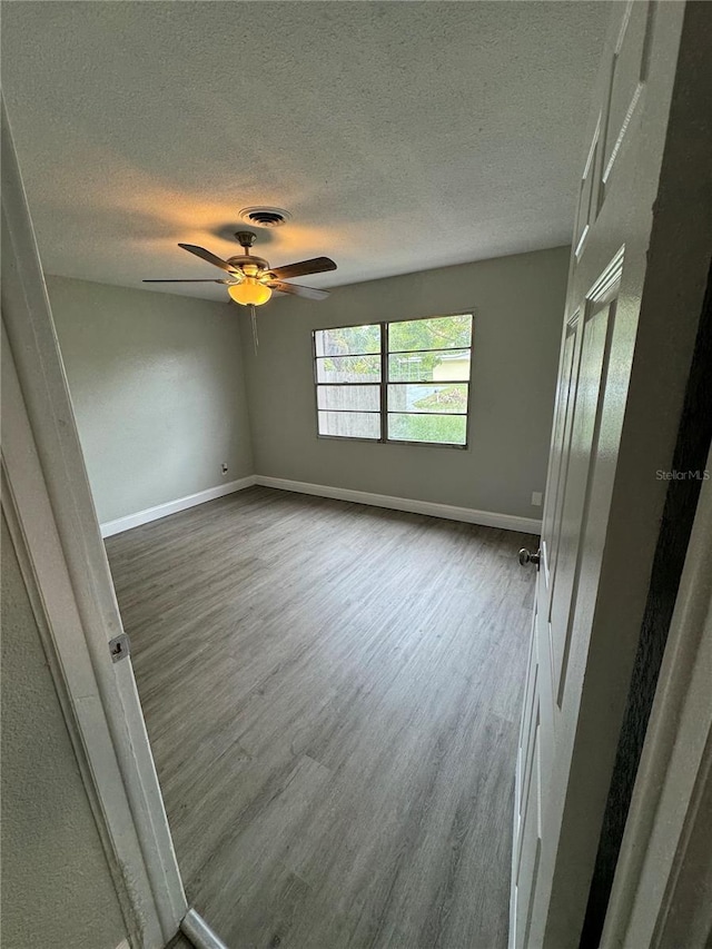 unfurnished room featuring wood-type flooring, ceiling fan, and a textured ceiling