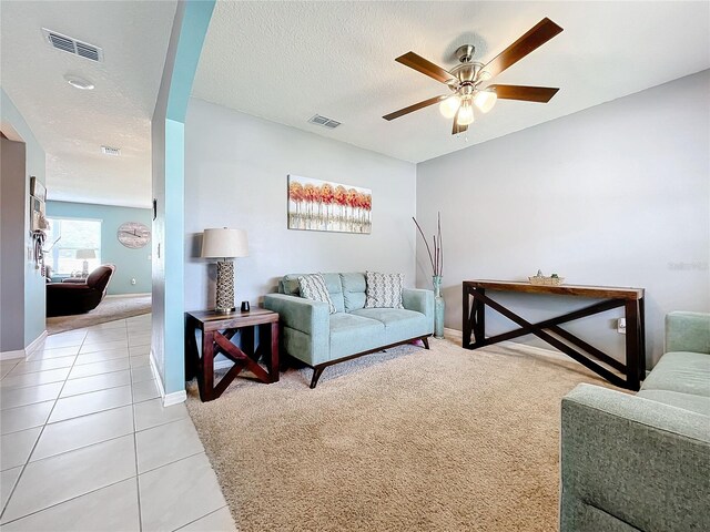 living room featuring ceiling fan, light tile patterned floors, and a textured ceiling