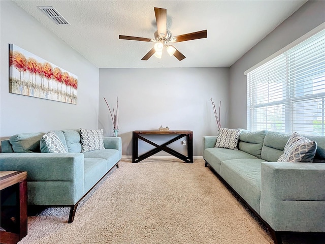 living room with ceiling fan, carpet floors, and a textured ceiling