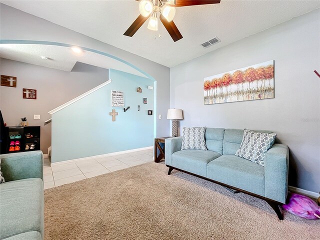 living room featuring light carpet, ceiling fan, and a textured ceiling