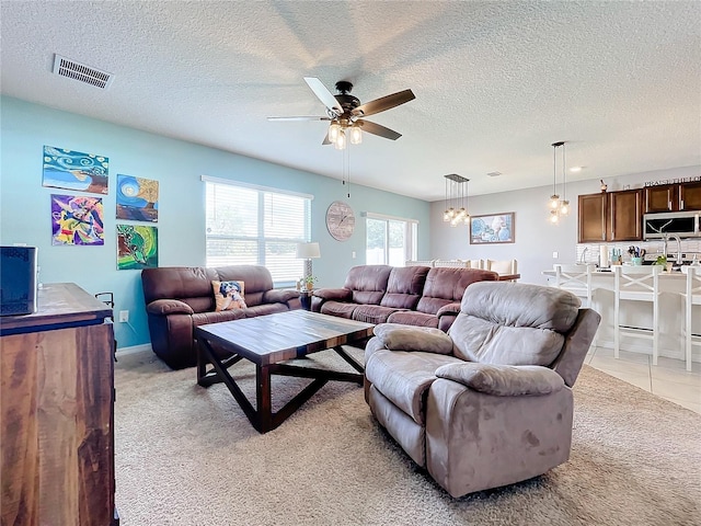 living room featuring light colored carpet, a textured ceiling, and ceiling fan with notable chandelier