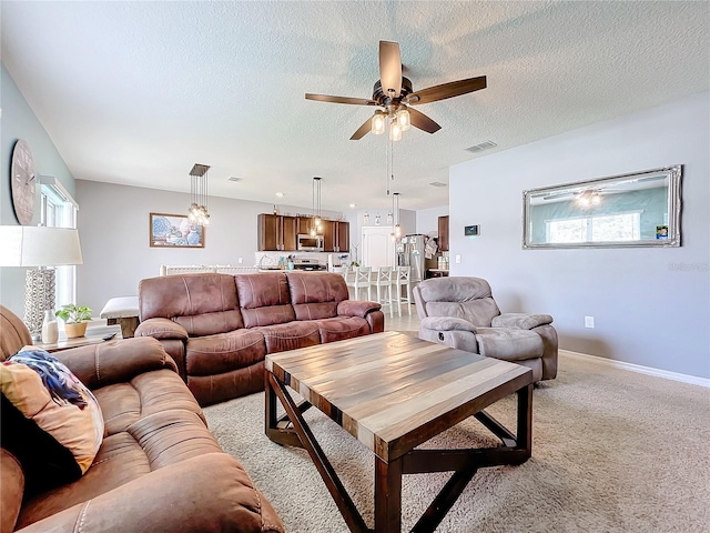 carpeted living room featuring a wealth of natural light, ceiling fan, and a textured ceiling