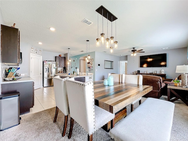 dining space featuring ceiling fan, a textured ceiling, and light carpet