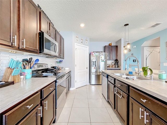 kitchen featuring pendant lighting, dark brown cabinets, sink, appliances with stainless steel finishes, and light tile patterned floors