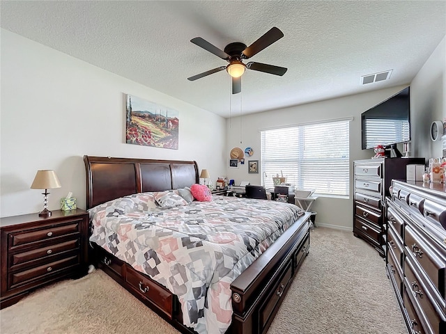 bedroom featuring light carpet, ceiling fan, and a textured ceiling